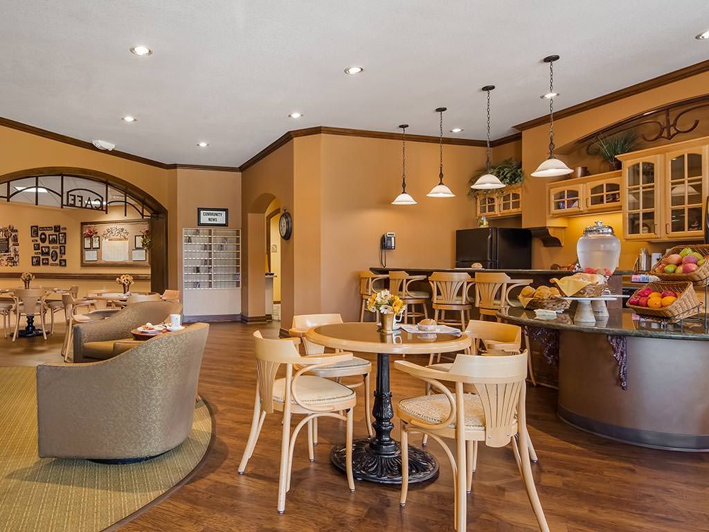 A modern kitchen with an open dining area featuring wooden furniture and pendant lighting.