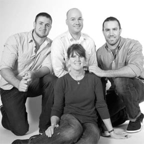 A black and white family portrait featuring three men and one woman in casual attire.