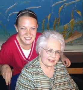 A caregiver and an elderly woman smiling together indoors.
