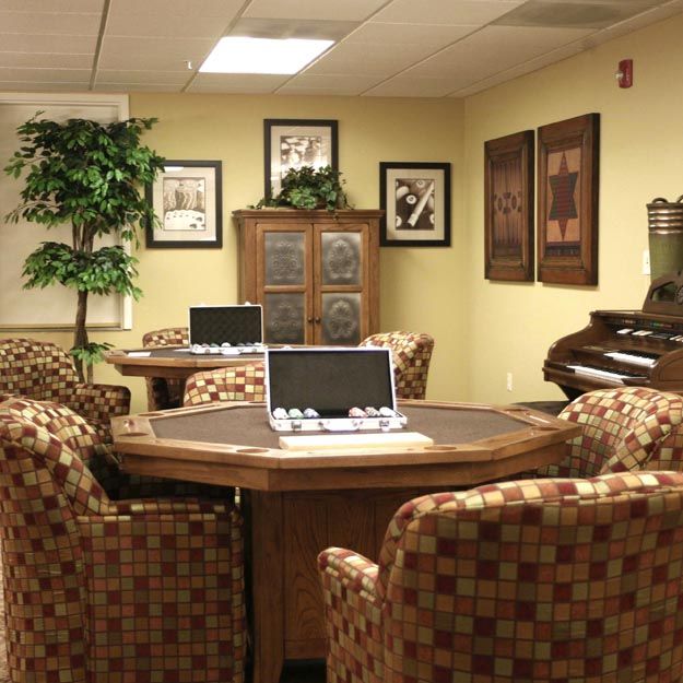 A cozy conference room with comfortable chairs, a laptop on the table, and decorative artwork on the walls.
