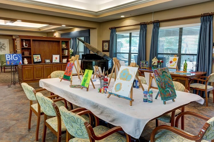 A room showcasing a variety of paintings on easels, set up for an art display or exhibition.