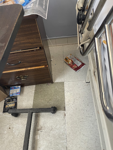 A kitchen scene showing a disorganized floor with a box and furniture.