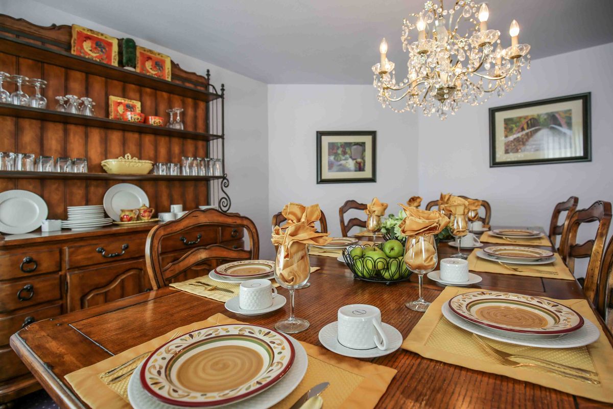 An elegant dining room with a beautifully set table, featuring a chandelier and decorative centerpiece.