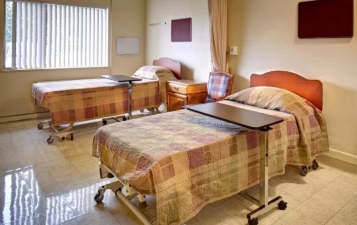 A hospital room with two neatly arranged beds and bedside tables.