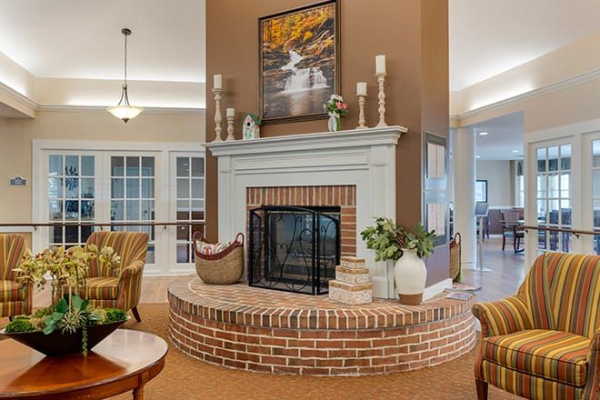 A cozy living room featuring a brick fireplace adorned with candles and plants.