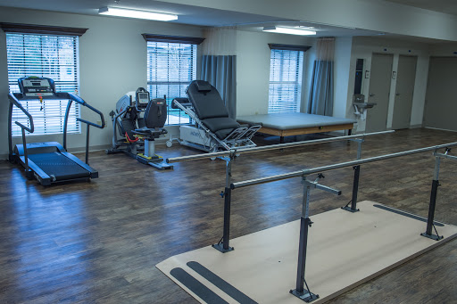 A well-equipped physical therapy room featuring exercise machines and parallel bars for rehabilitation.