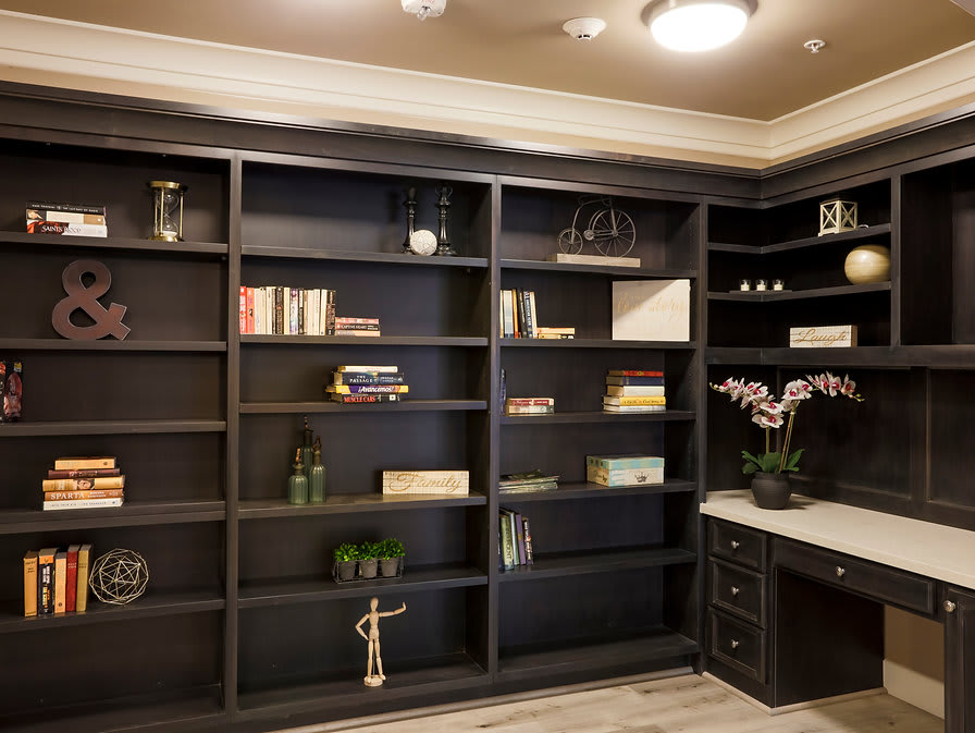 A modern home office with built-in dark wood bookshelves and elegant decor.
