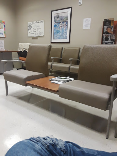 A view of a waiting area featuring padded chairs and a small table.