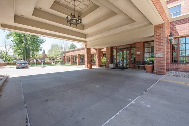 The entrance to a building with a covered driveway and glass doors.