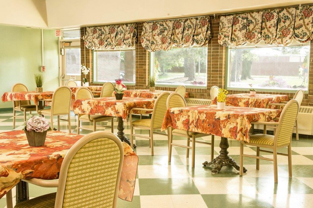 A cozy dining room with floral tablecloths and checkered flooring.