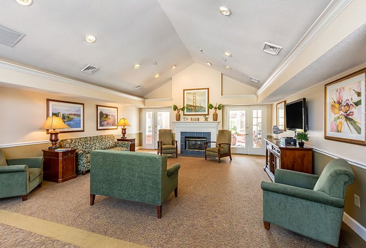 A spacious and elegantly decorated living room with sofas, chairs, a fireplace, and artwork on the walls.