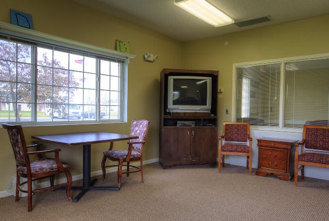 A waiting room with a television, chairs, and a table.