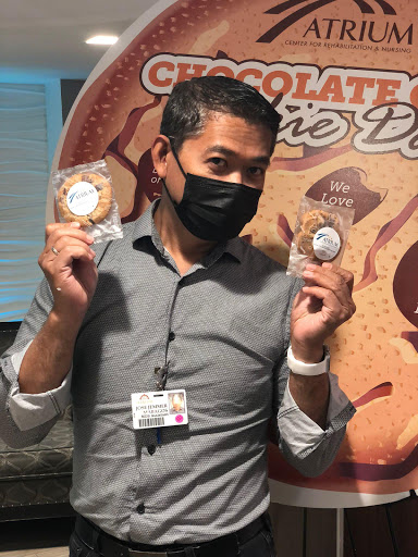 A man holding two cookies and smiling, wearing a mask.