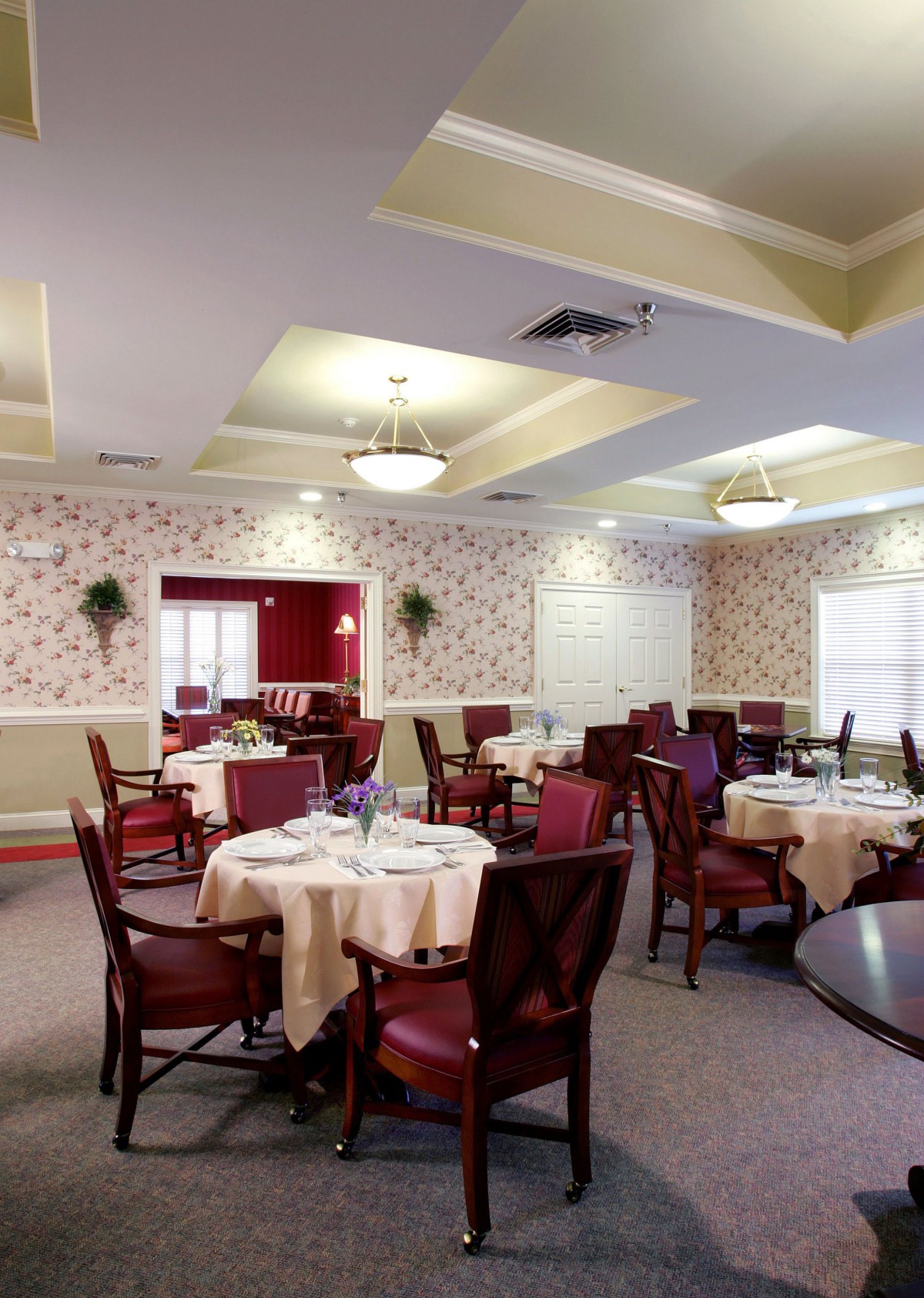 An elegant dining room setup with multiple tables and chairs, featuring stylish lighting and decor.