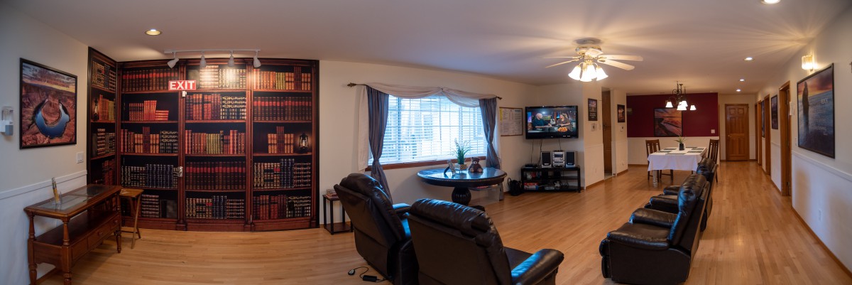 A cozy living room with leather armchairs, a television, and a large window adorned with curtains.