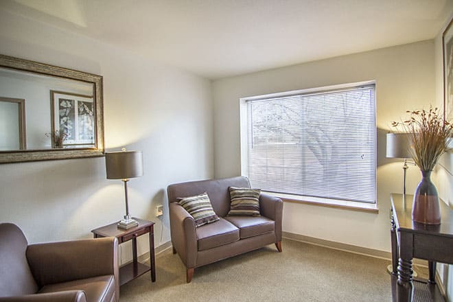 A cozy and minimalist living room with a sofa, armchair, and large window.