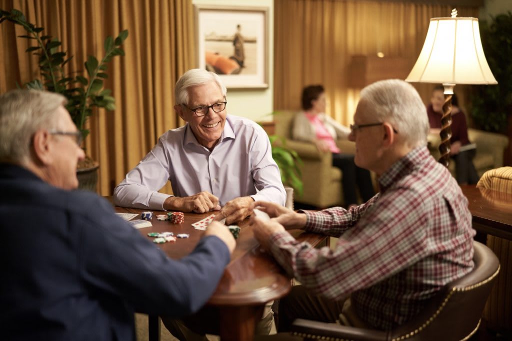 A group of elderly friends enjoying a card game together indoors.