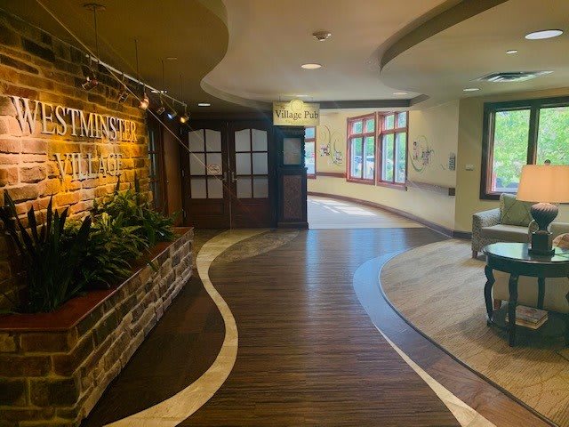 A warmly lit hallway with a brick feature wall and curved wooden flooring.