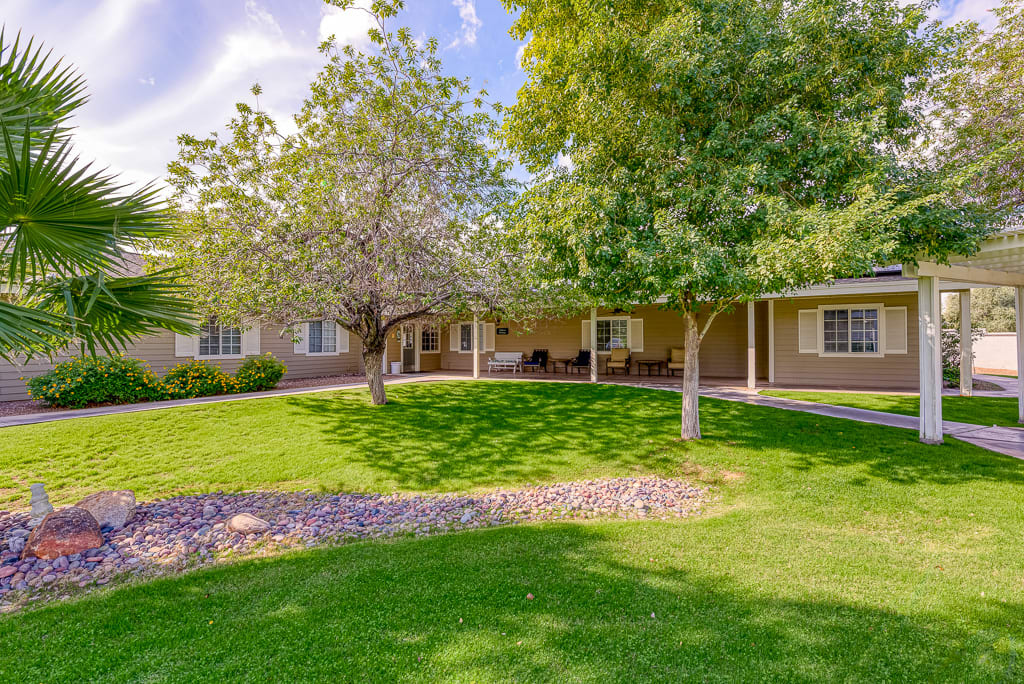 A sunny day view of a house with a well-maintained yard and mature trees.