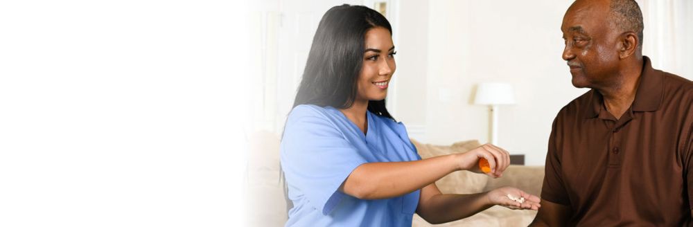 A smiling healthcare professional in blue scrubs interacting with a patient.