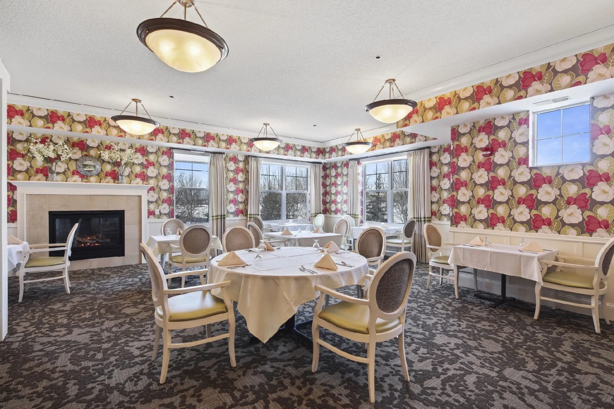 An elegant dining room with floral wallpaper and stylish seating arrangements.