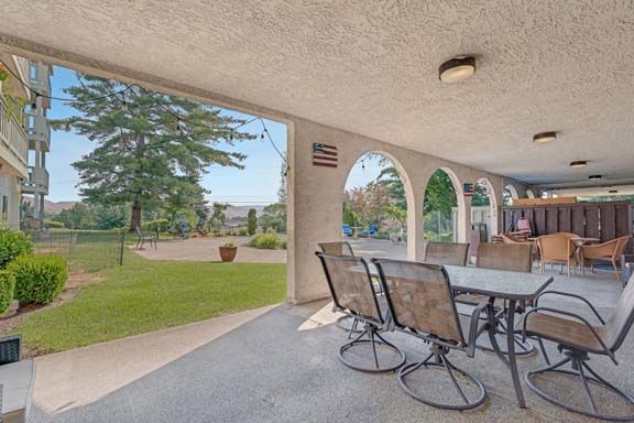 A spacious patio with outdoor seating, offering a view of the garden and lawn through decorative arches.