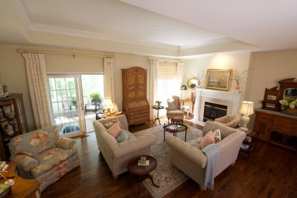 A cozy living room with elegant decor, featuring sofas, armchairs, a fireplace, and abundant natural light.