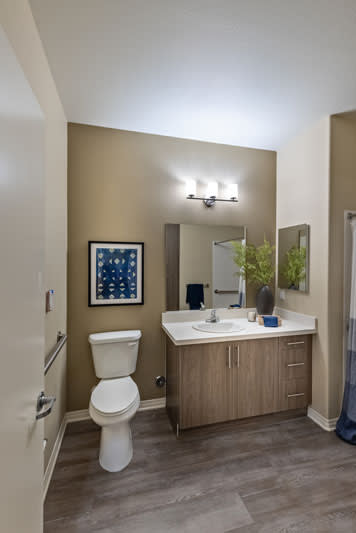 A modern bathroom with a vanity, mirror, and wall art.