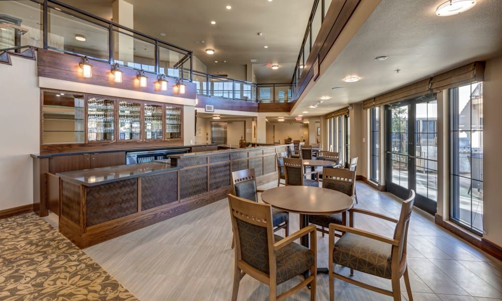 A modern restaurant interior featuring a spacious dining area with tables, chairs, and a bar counter.