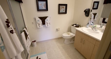 A clean bathroom with decorative elements, including towels and framed artwork.
