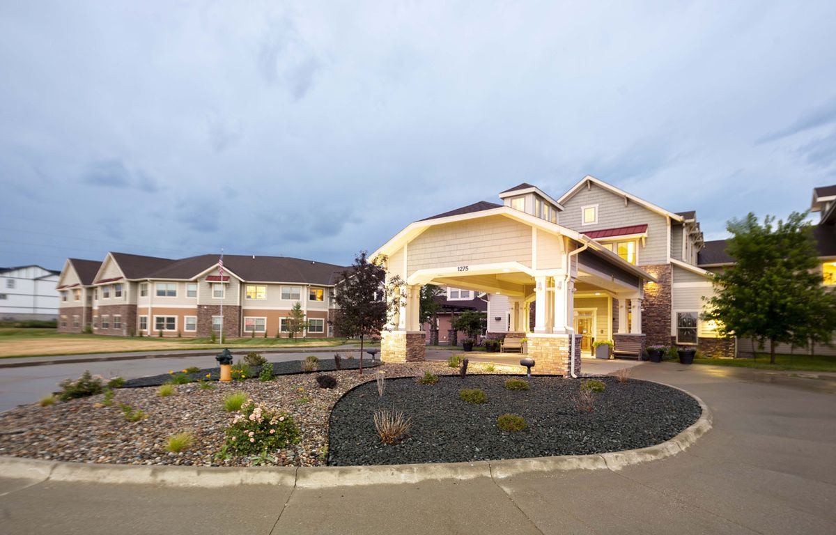 A well-lit residential building with landscaping at dusk.