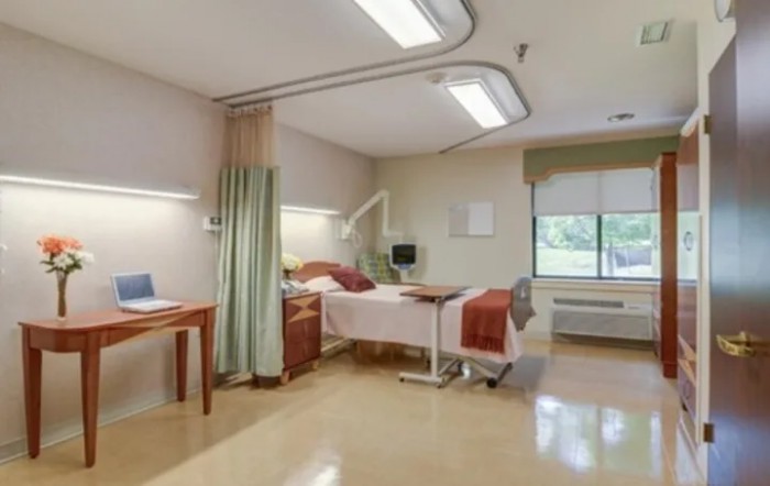 A clean and well-equipped hospital room with a bed and medical apparatus.
