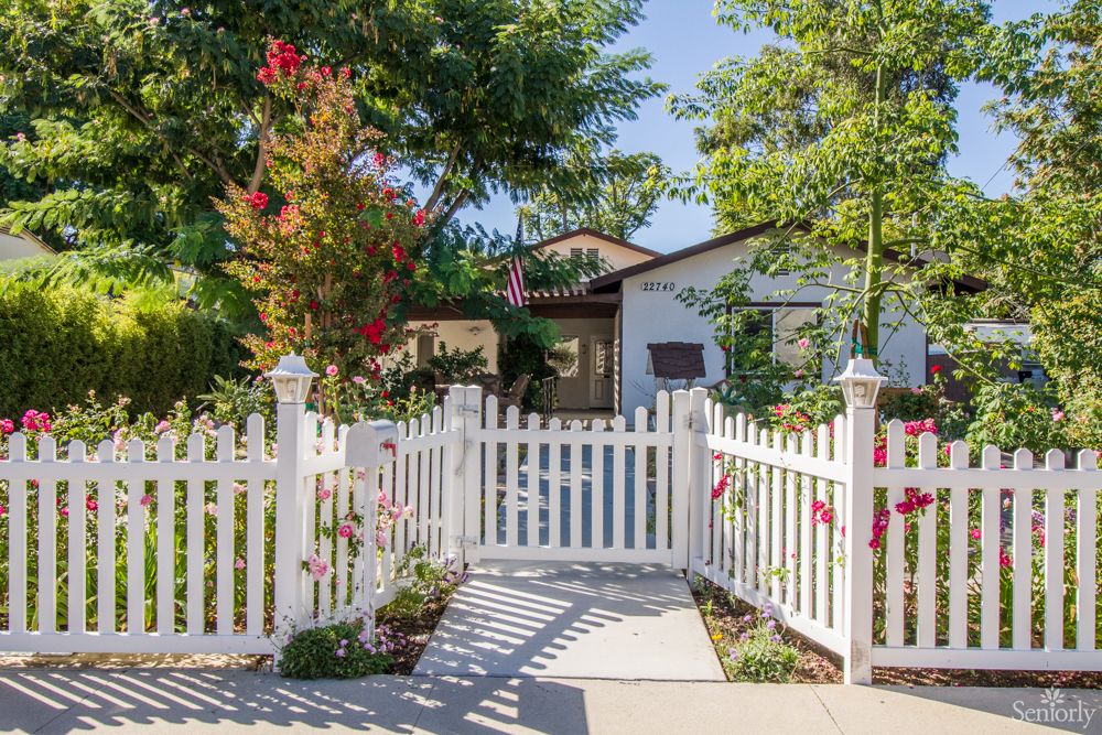 A charming suburban house with a white picket fence and garden.