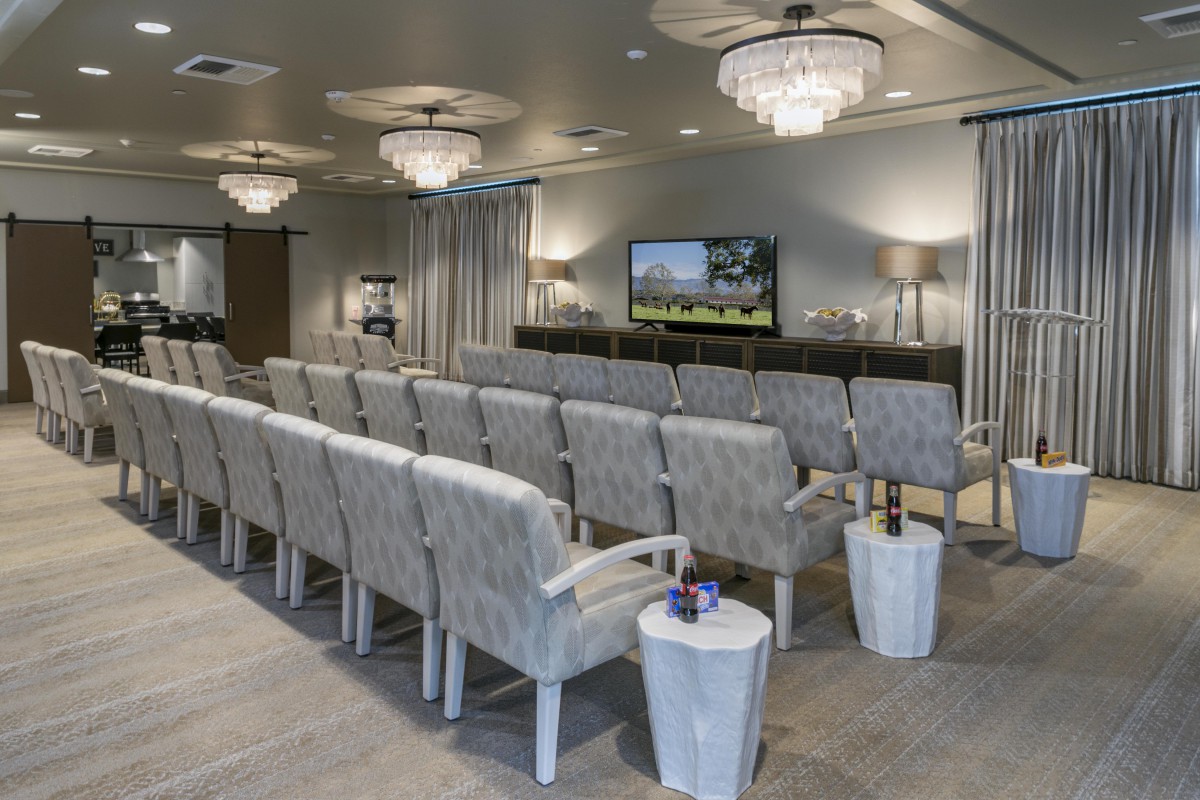 A well-lit conference room with arranged seating and a television at the front.