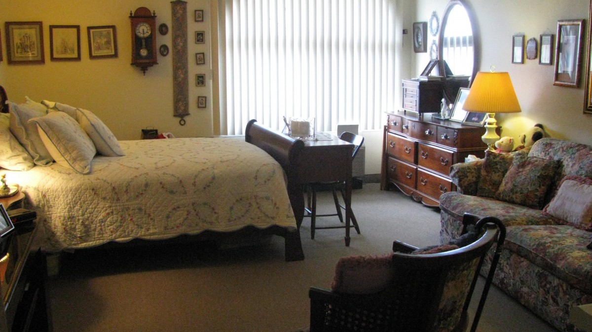 A cozy bedroom with antique furniture and soft lighting through vertical blinds.