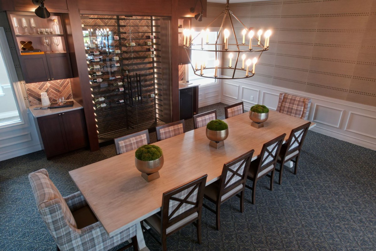 A stylish dining room featuring a long table with chairs, elegant chandelier, and decorative plants.