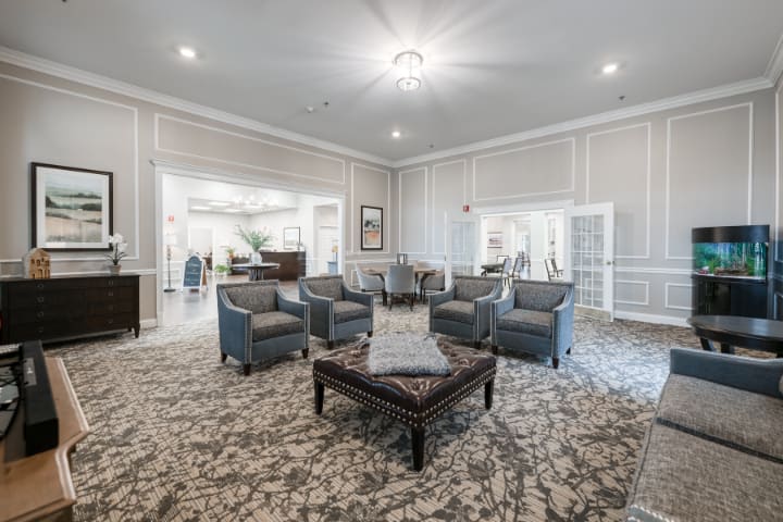 A spacious and elegantly decorated living room with a set of armchairs arranged around a central table on a patterned carpet.