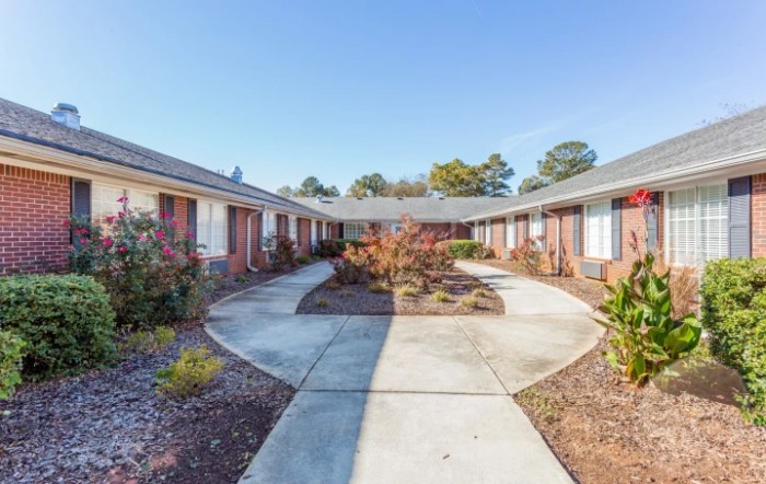 A courtyard surrounded by a residential building with a central sidewalk and landscaped areas.