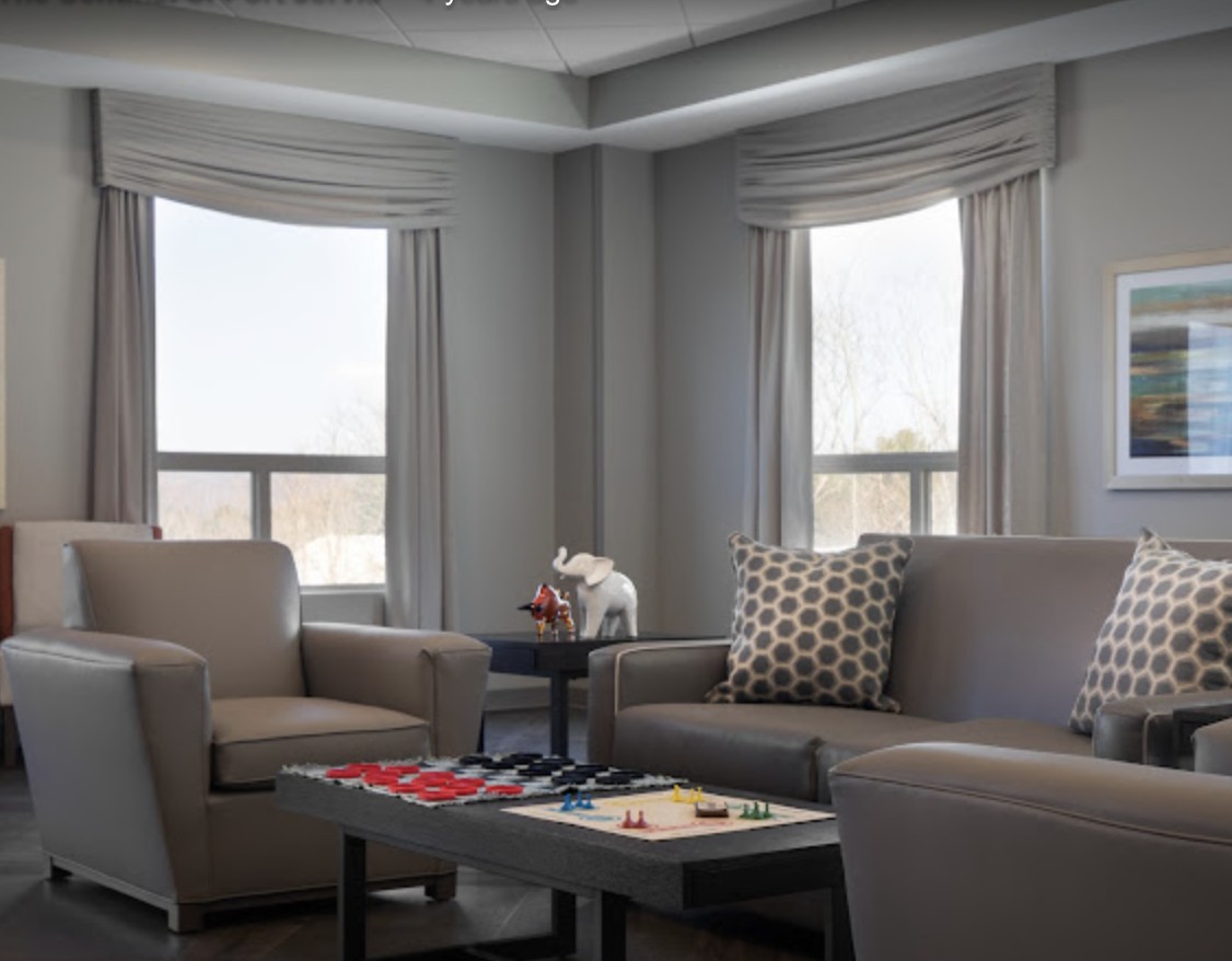 A modern living room with comfortable seating and a coffee table by large windows.