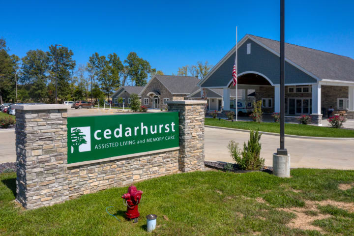 An assisted living facility with a prominent sign for Cedarhurst, surrounded by greenery on a sunny day.