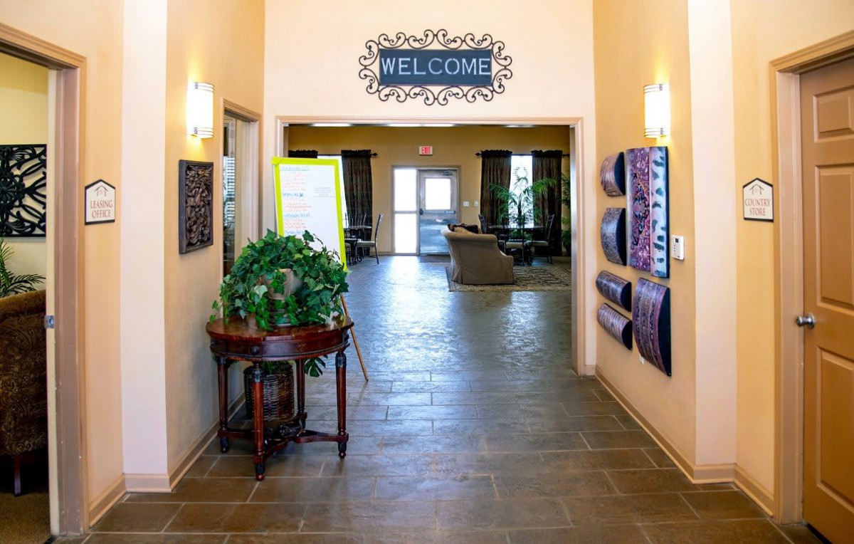 An inviting entrance hallway with a 'Welcome' sign, decorated with plants and artwork.
