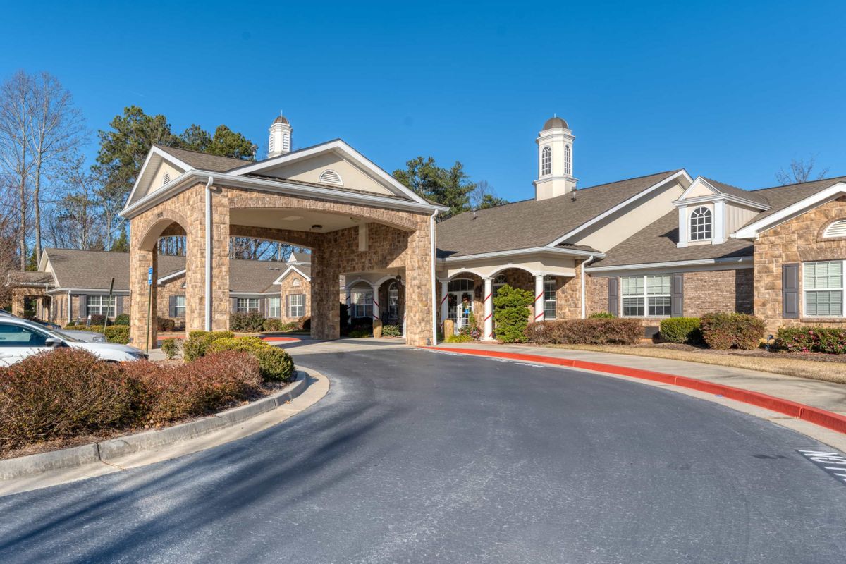 A residential building with a covered entrance and driveway under a clear blue sky.