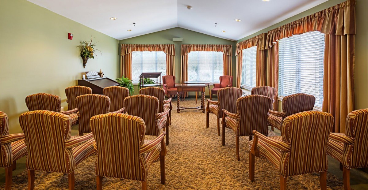 A well-arranged meeting room with rows of striped chairs and large windows with curtains.