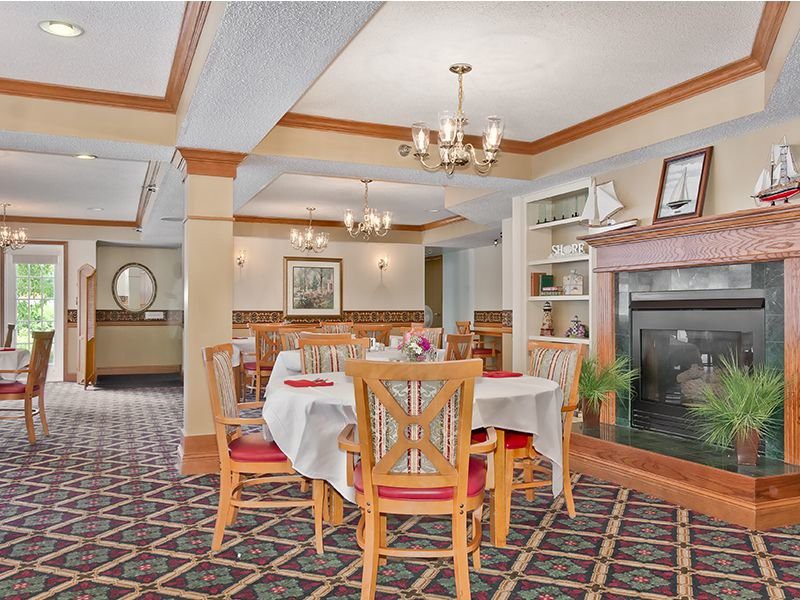 A cozy restaurant interior featuring a dining area with tables and chairs, a fireplace, and elegant chandeliers.