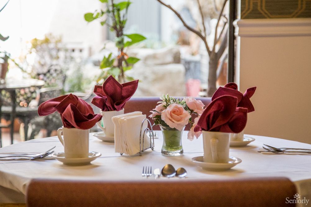 An elegantly set table with decorative napkins, flowers, and cups in a cozy restaurant environment.