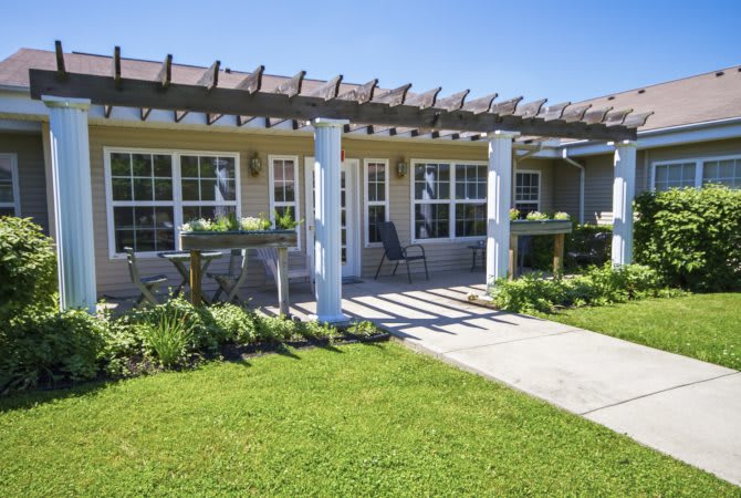 A cozy house with a pergola-covered patio and well-maintained lawn.