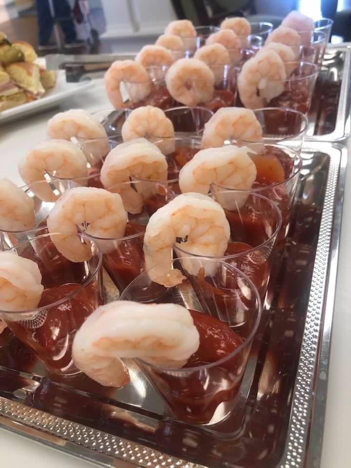 Shrimp cocktails arranged in individual cups, ready to be served at a gathering.