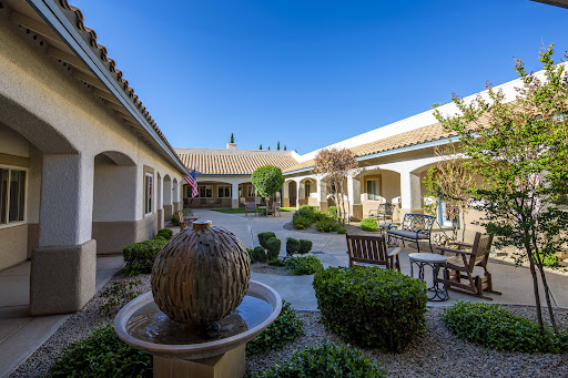 A serene courtyard featuring a central fountain, surrounded by lush greenery and comfortable seating, perfect for relaxation.