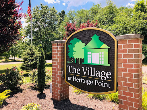 Entrance sign of The Village at Heritage Point, surrounded by lush greenery.