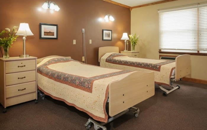 A hospital room featuring two neatly made beds with wooden frames and medical equipment.